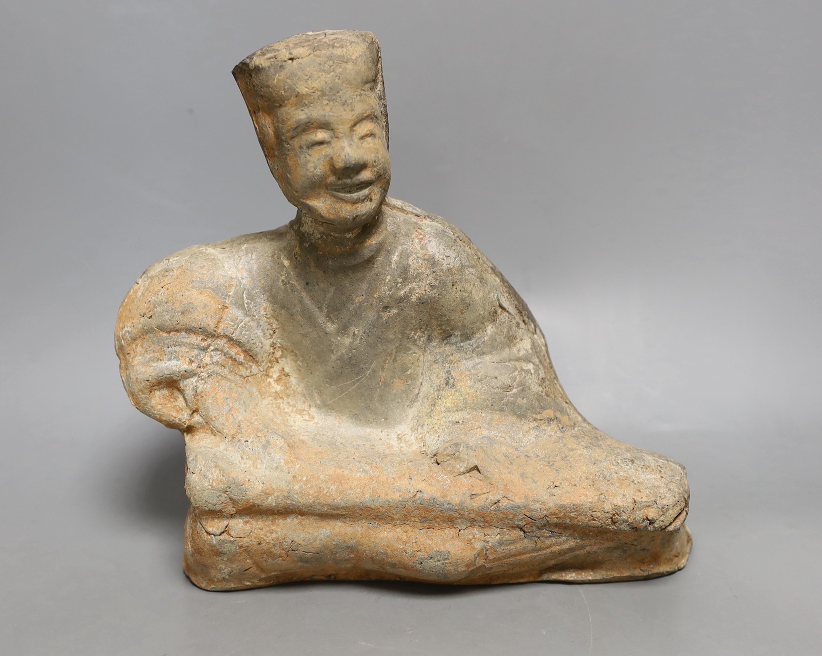 A Chinese grey pottery figure of a seated musician, Han dynasty (200BCE to 220CE) or later, 25cm high